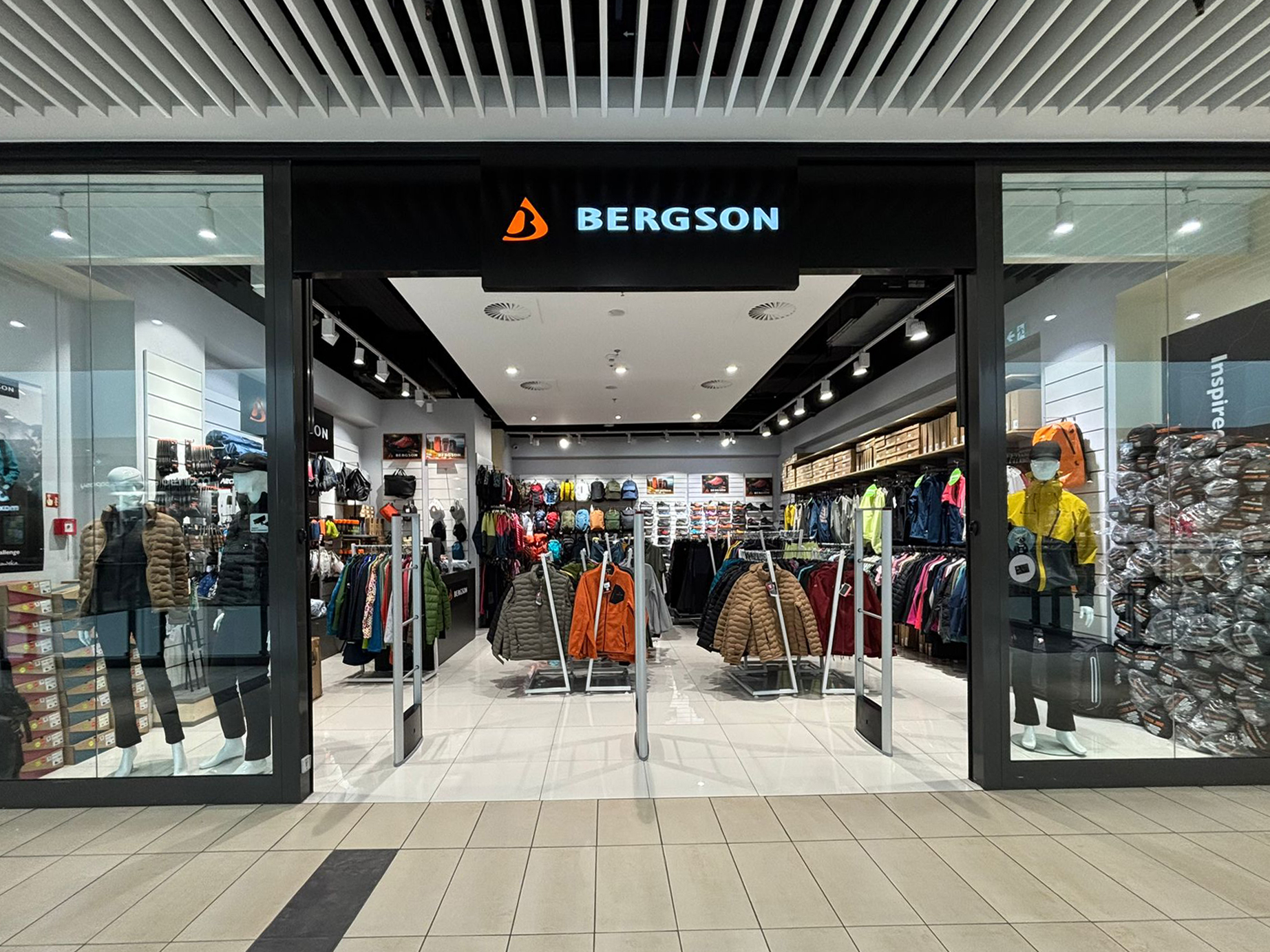 Czarna witryna sklepu Bergson z logo nad wejściem i wystawą odzieży sportowej w tle.