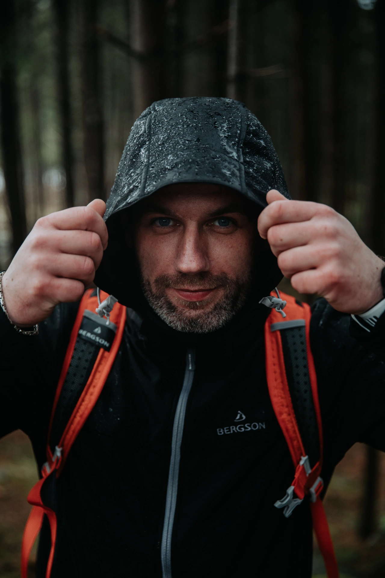 mężczyzna zasłania się przed deszczem,ma ubrany kaptur i kurtke przeciwdeszczową